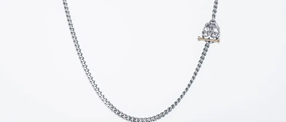 A silver chain necklace with a small pendant on a white ground