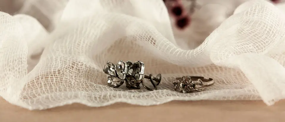 Two old silver rings set with small stones resting on white gauze