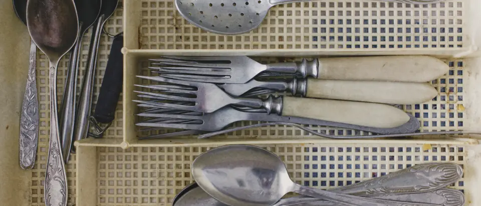 Old silver spoons, forks with bone handles and a slotted spoon sorted in a cutlery tray