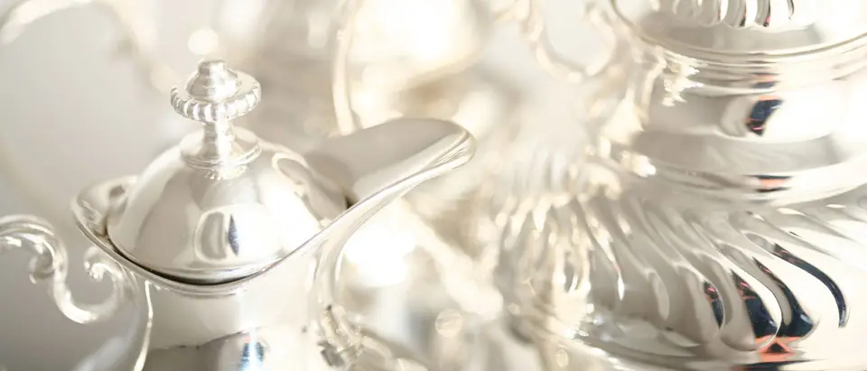 A polished silver teapot and a fluted silver pot catching soft light