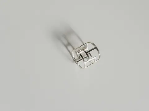 A plain open silver ring casting a soft shadow on a pale grey ground