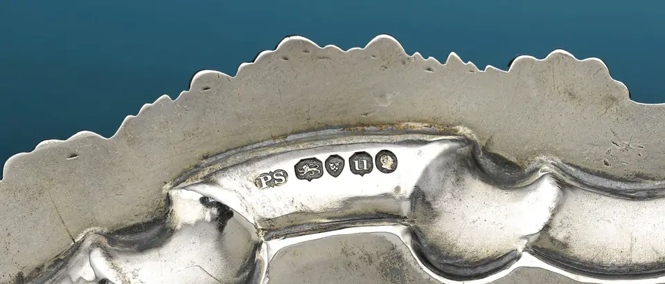 A row of London hallmarks, the maker's PS, the lion passant for sterling, the leopard's head, the date letter and the king's head, struck on the rim of a silver tray