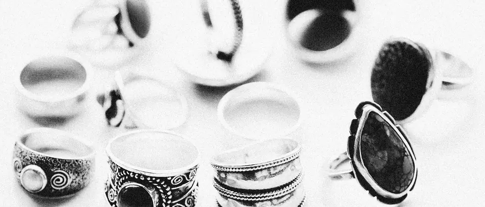 Handmade silver rings set with dark stones on a white ground