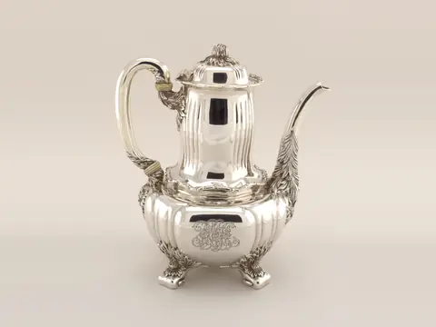 A tall sterling coffeepot by Tiffany & Co. with a reeded body, a flowered spout and four leafy feet